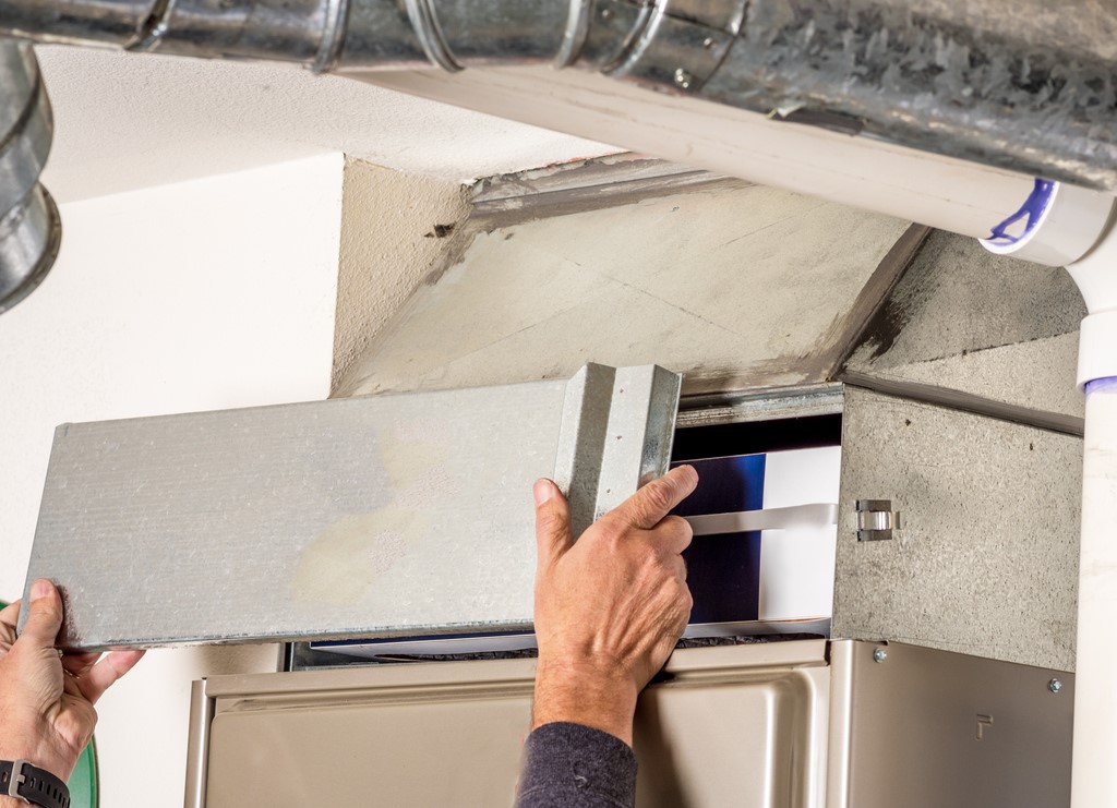 Technician removing furnace access panel for a filter change